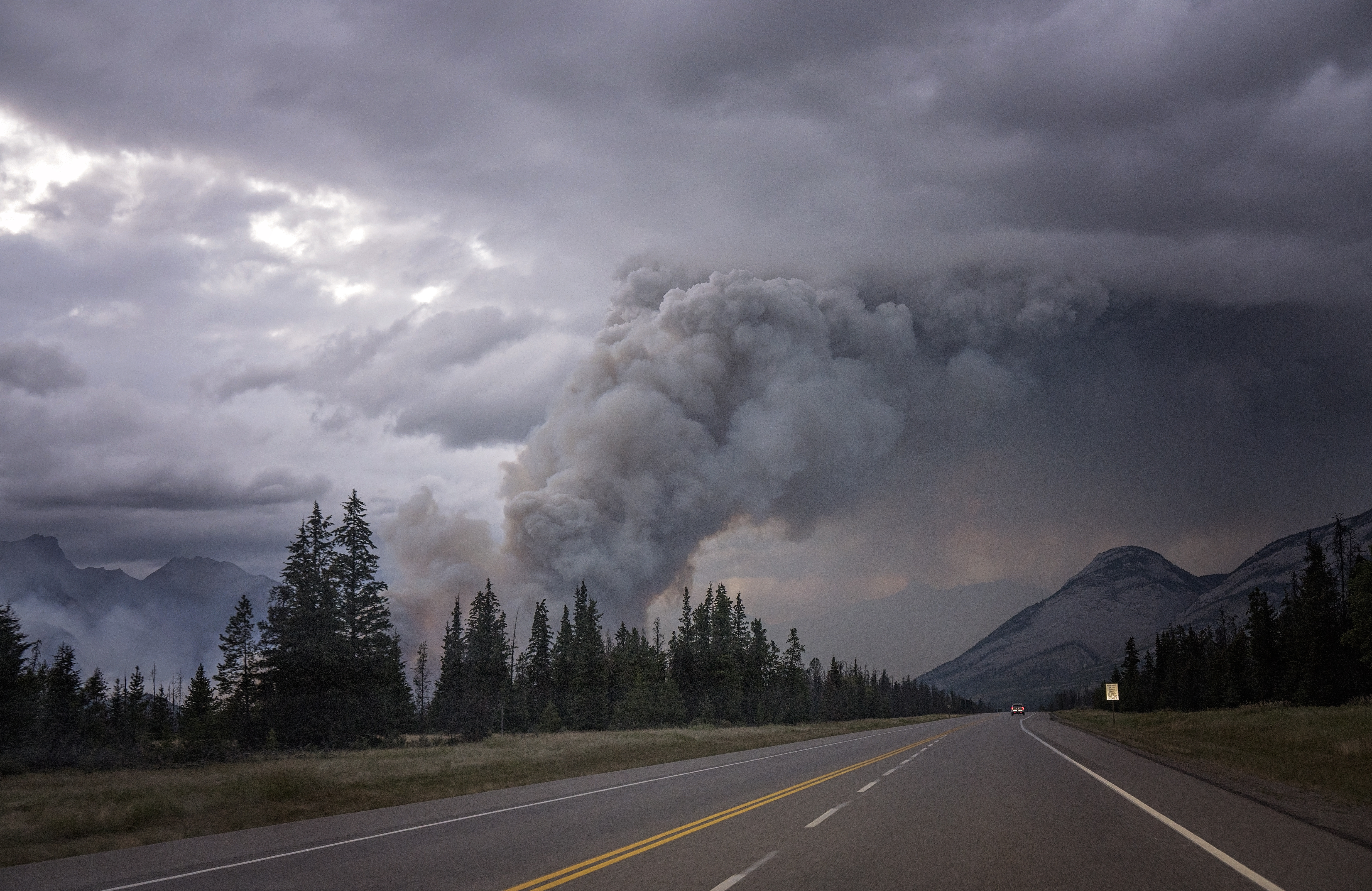 Plumes of smoke from a wildfire blow over a highway.