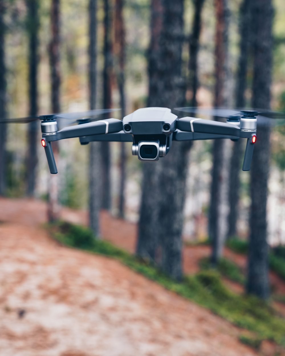 Modern Drone with camera flying in the forest.