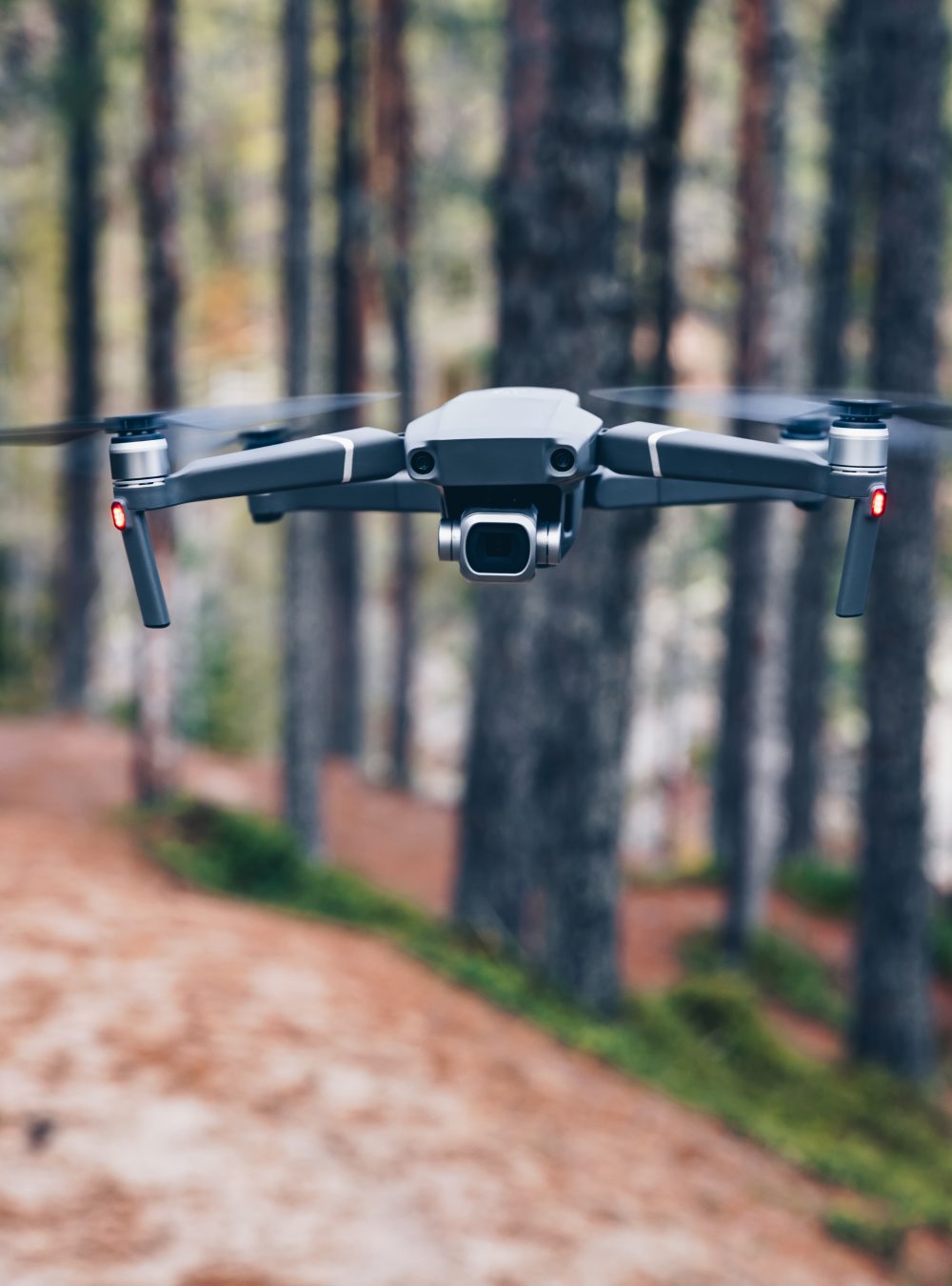 Modern Drone with camera flying in the forest.